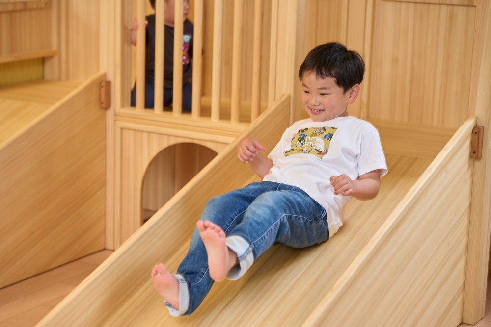 子どもがアスレチック滑り台を滑る様子