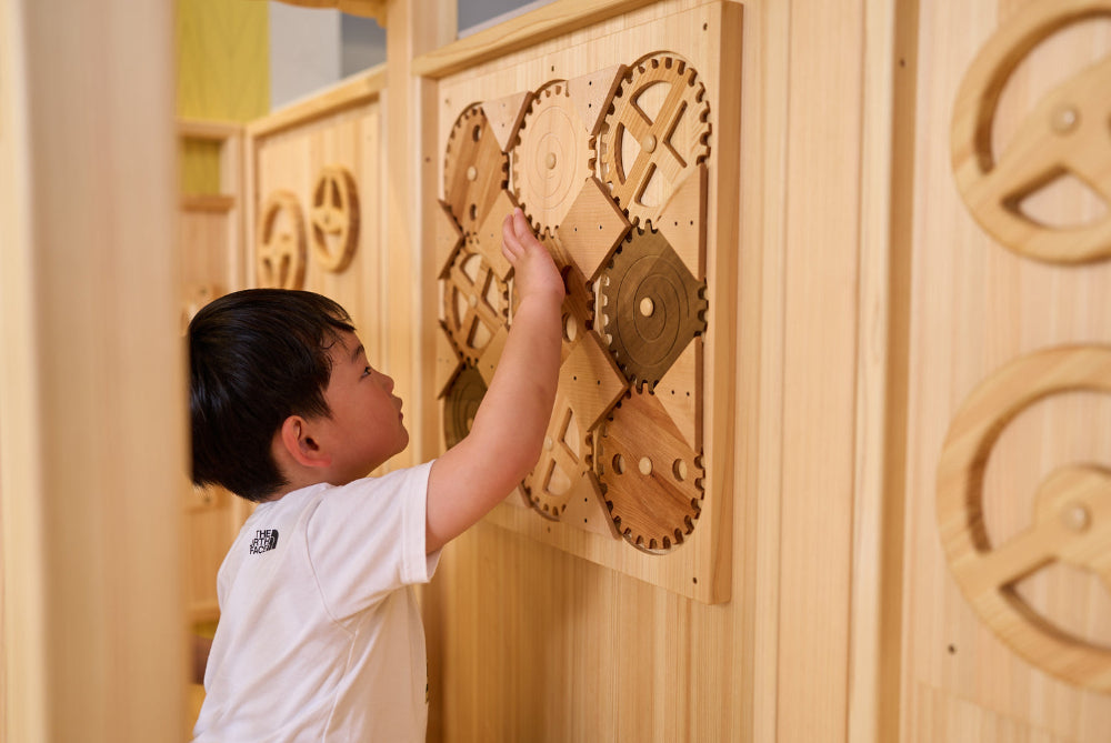 子どもが壁面のアクティビティボードで遊ぶ様子