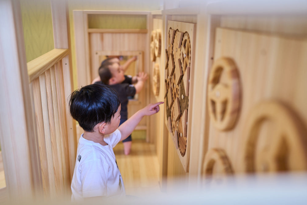 子どもが壁面のアクティビティボードで遊ぶ様子