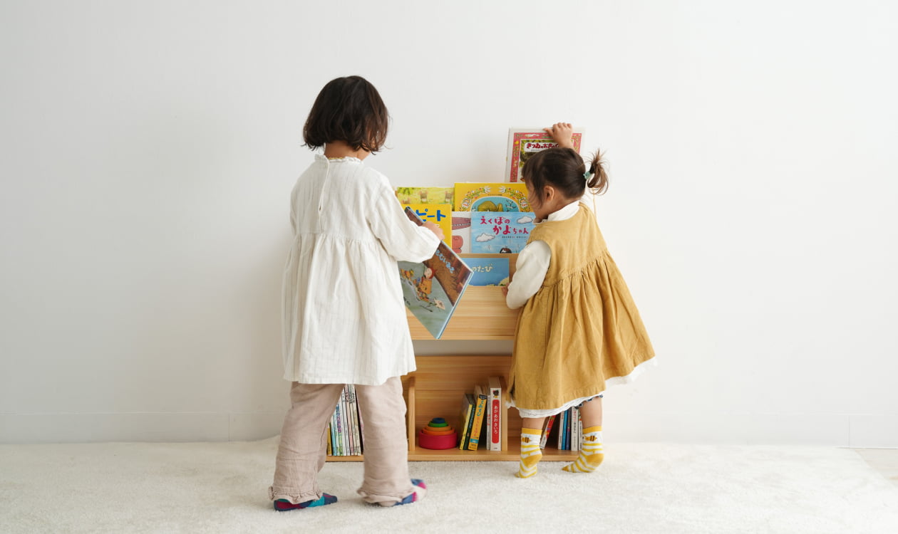木製家具 木製絵本棚から子どもが絵本を取り出している様子