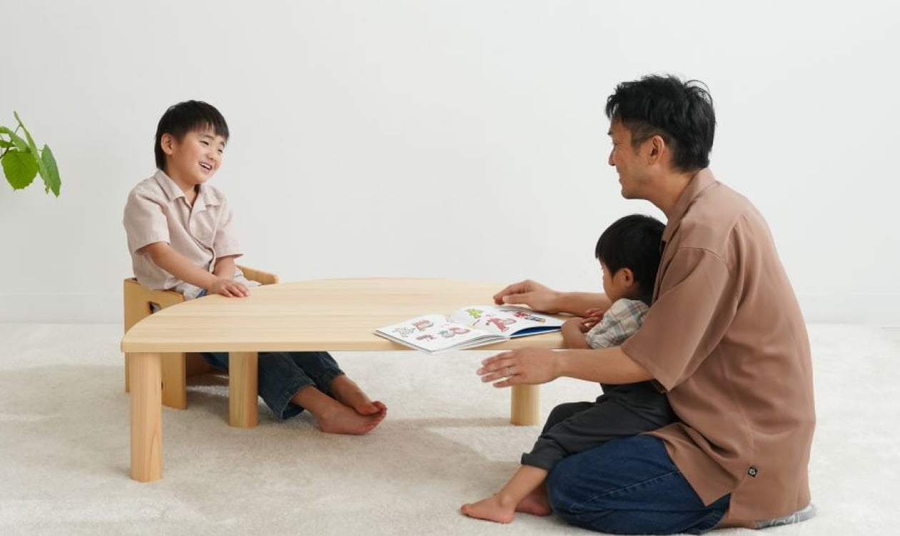 木製家具　木製テーブルを家族で囲んでいる様子