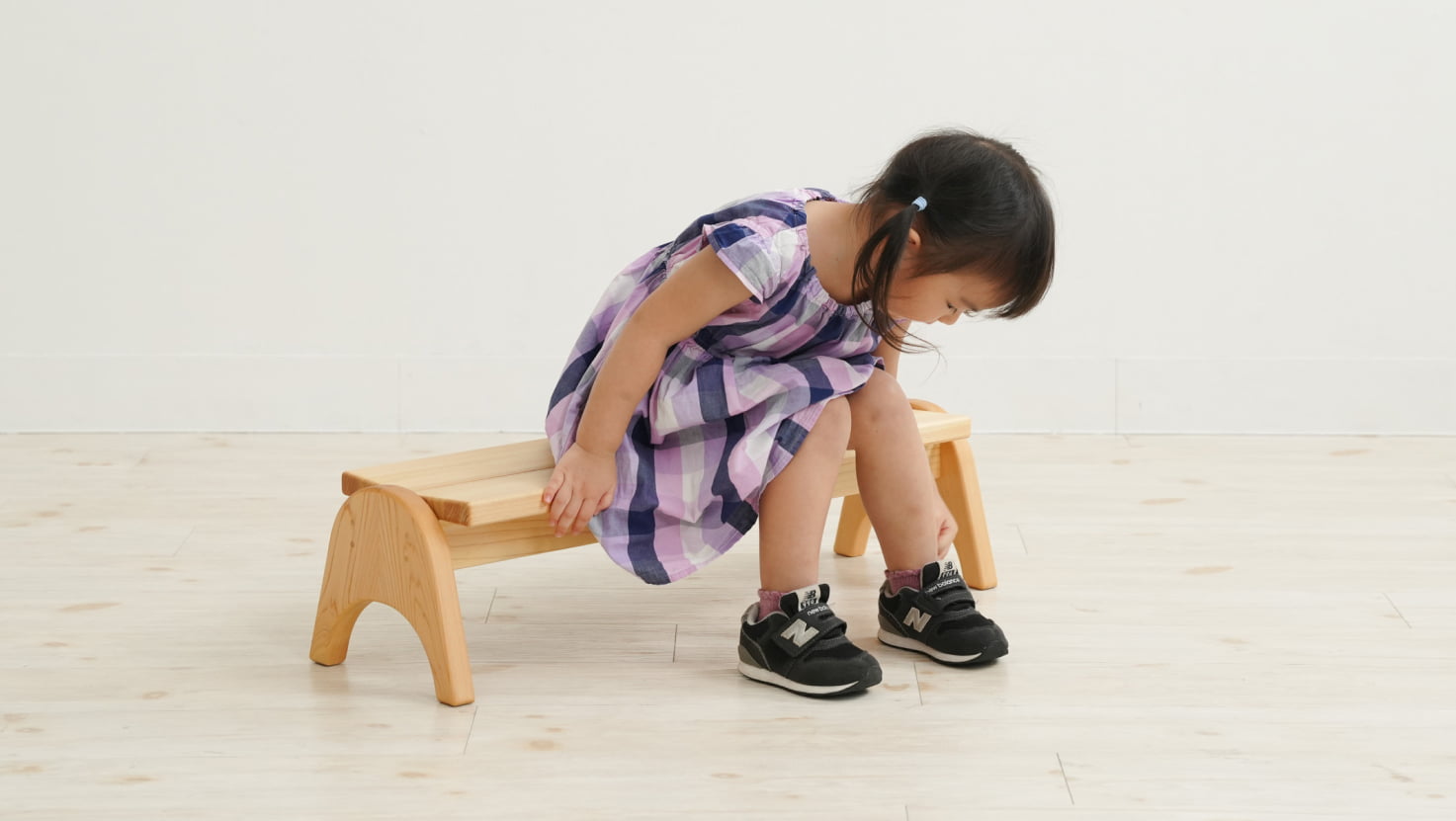 木製家具 木製スツールに座って子どもが靴を履いている様子
